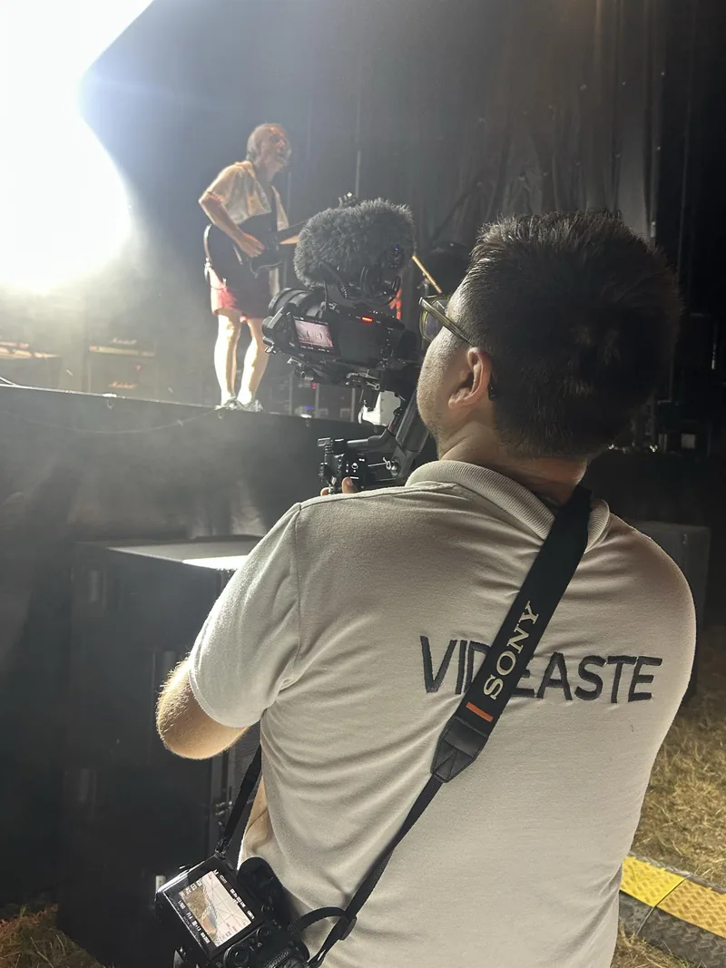 Corentin Maïly filmant un concert en pied de scène lors d’un festival associatif